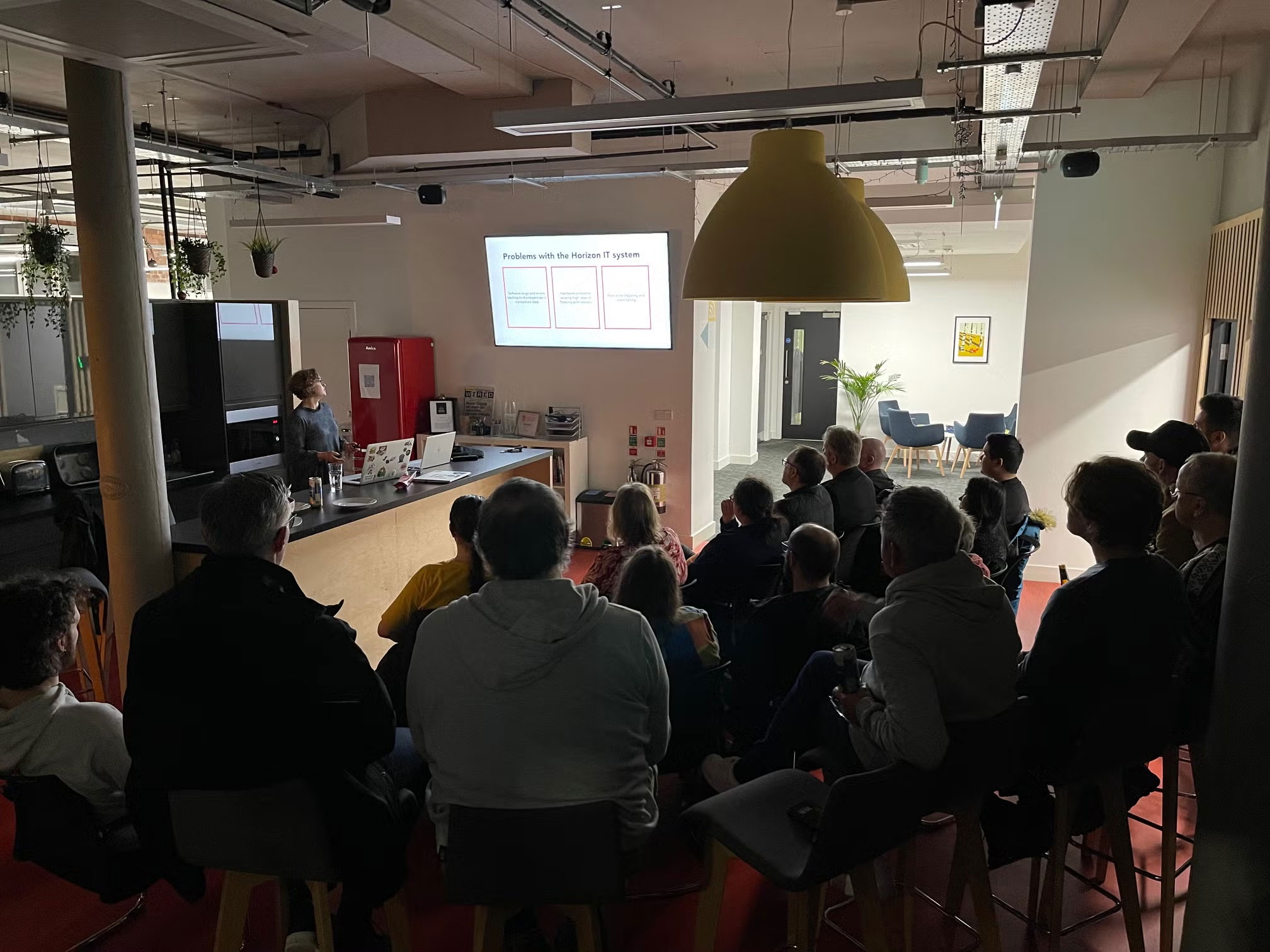 Amy presenting a talk in front of a crowd seated on chairs
