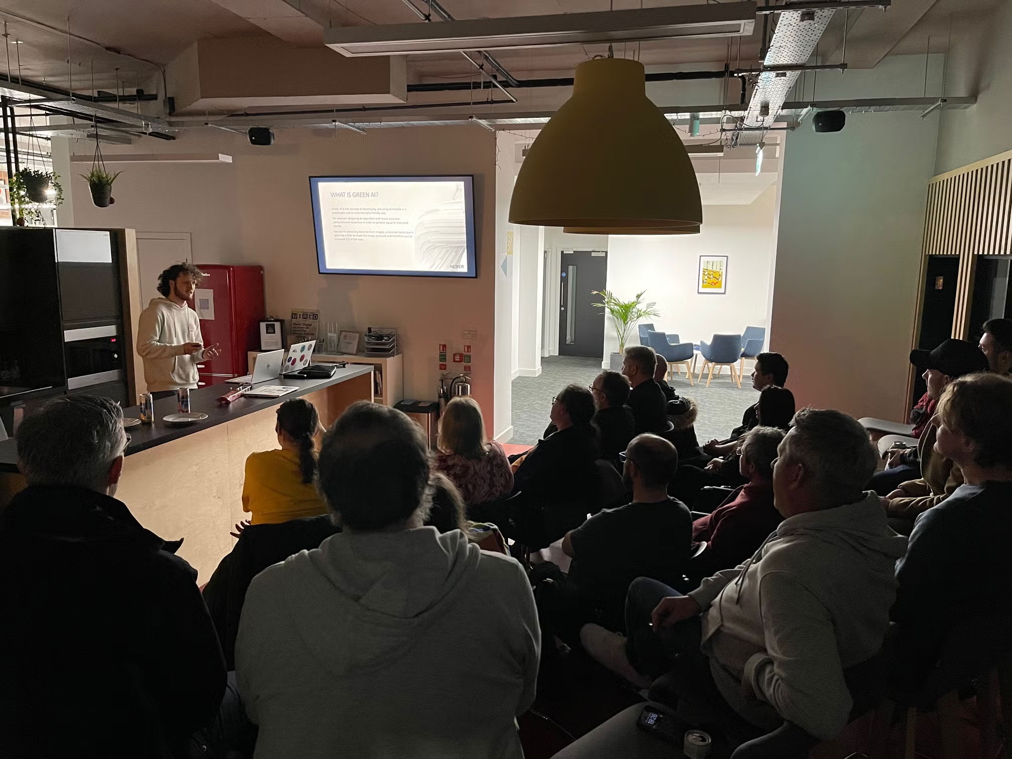 Harry presenting a talk in front of a crowd seated on chairs