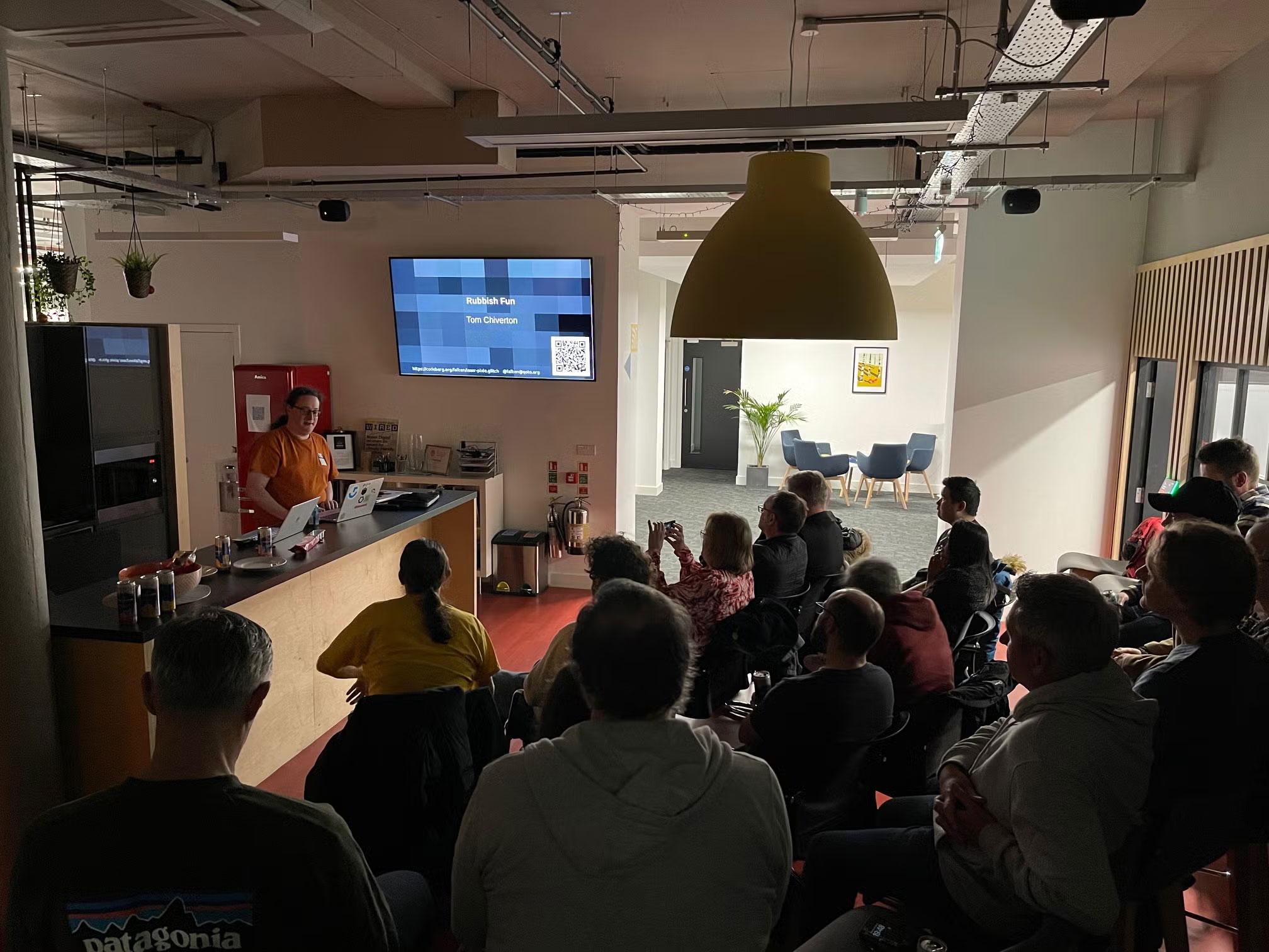 Tom presenting a talk in front of a crowd seated on chairs