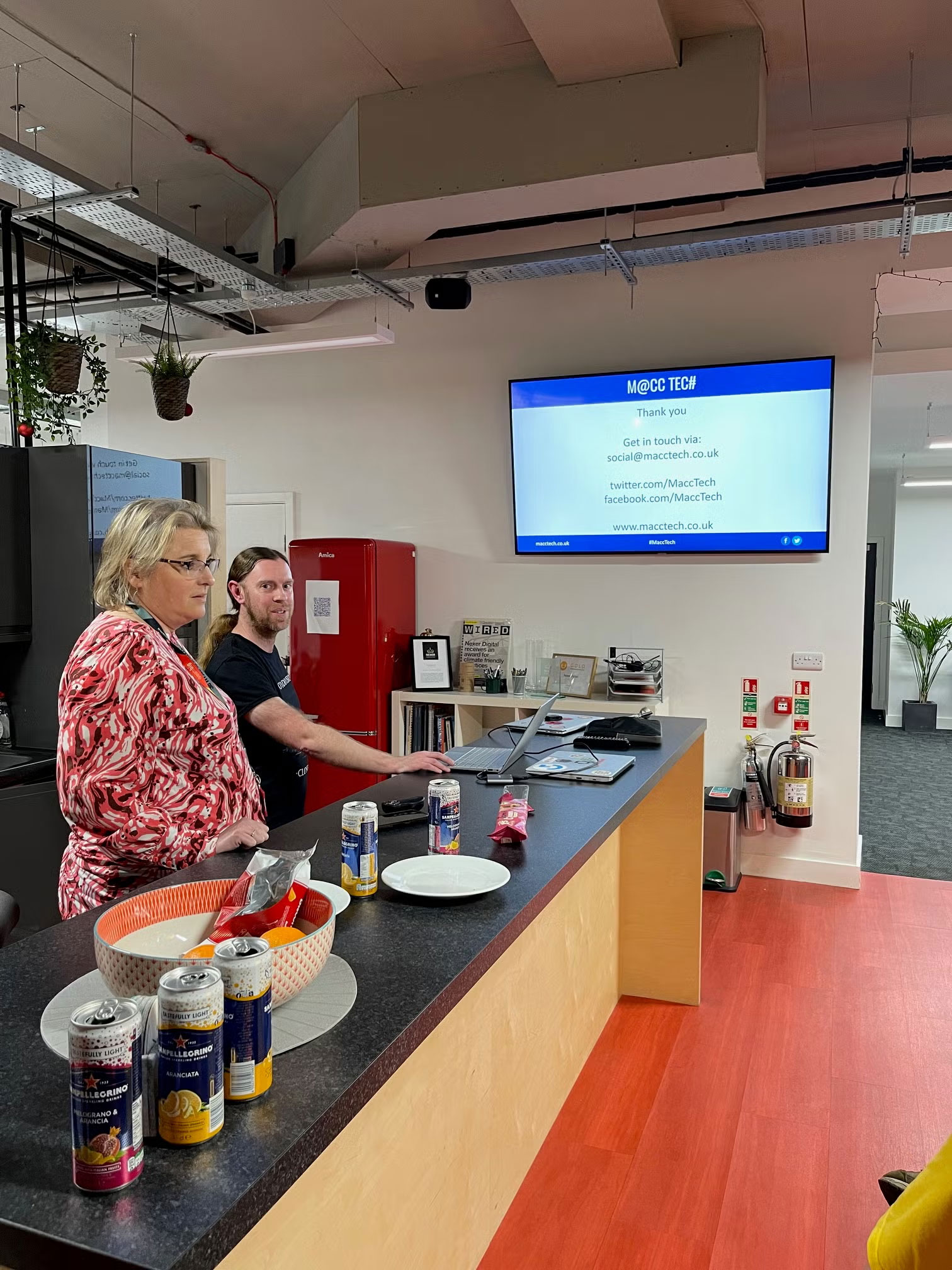 Rachel and Mike concluding the session standing by a counter in front of a screen on a wall