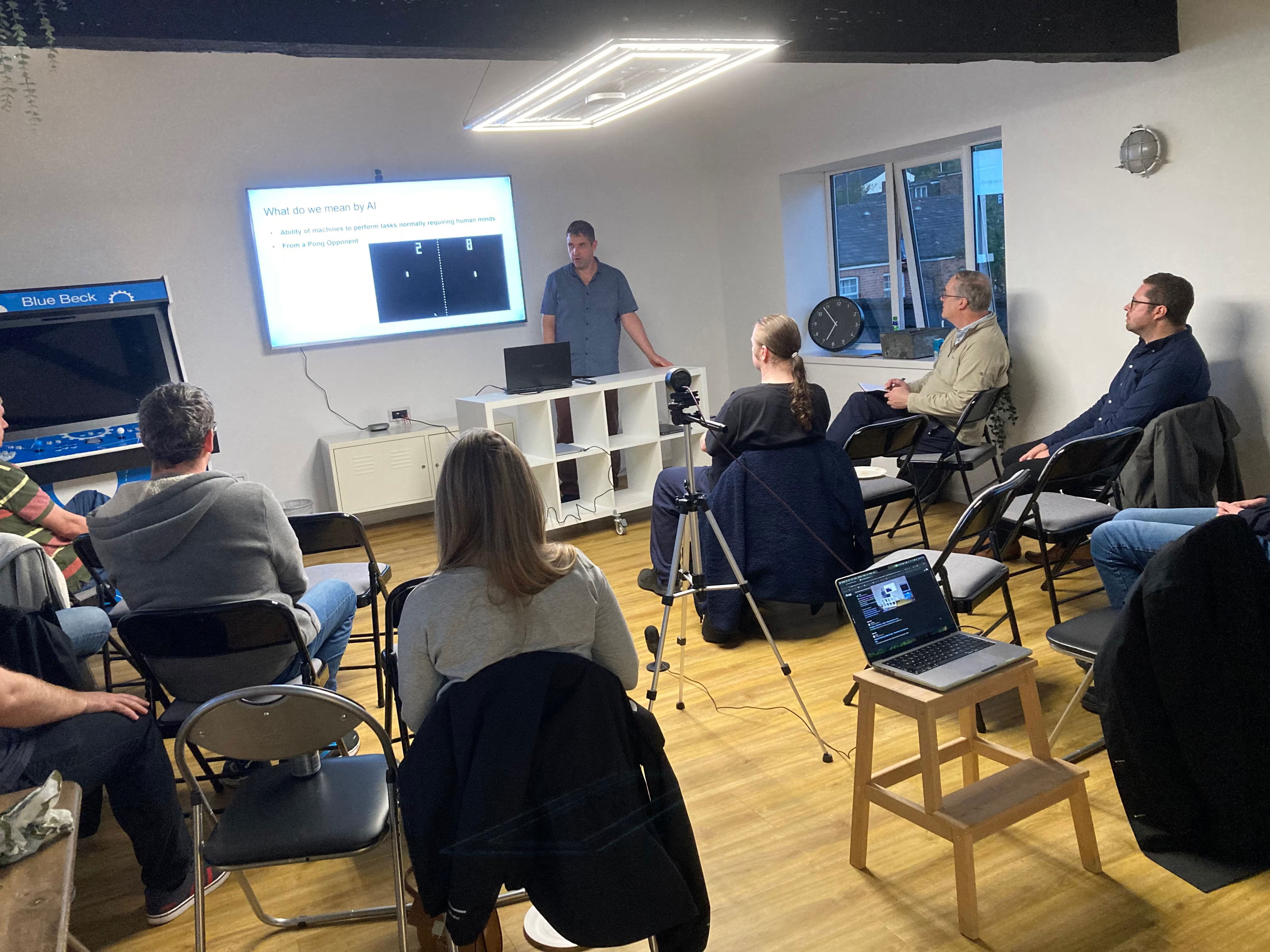 Audience watching Richard present slide 'What do we mean by AI'