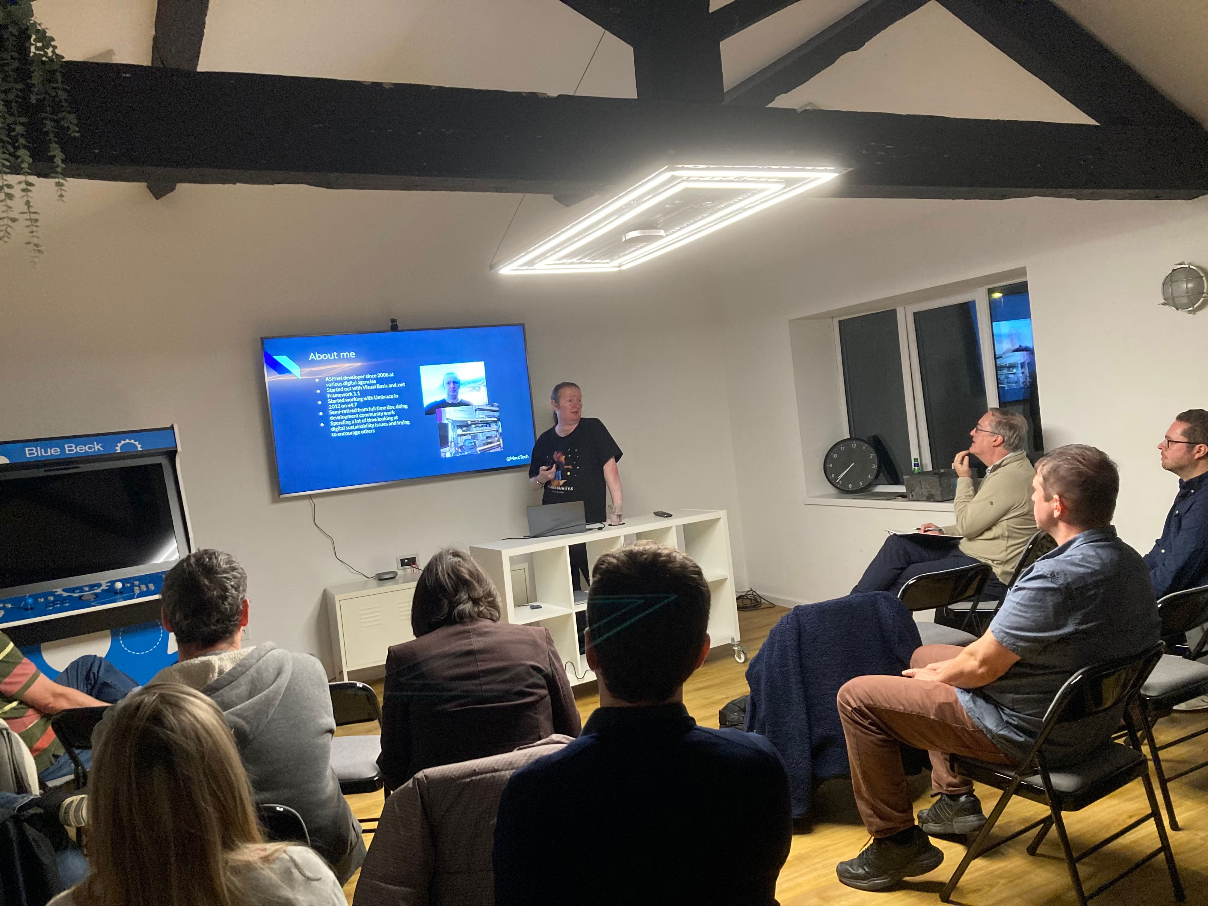 Terence presenting his 'About me' slide, stood aside the presentation screen. Audience watching.