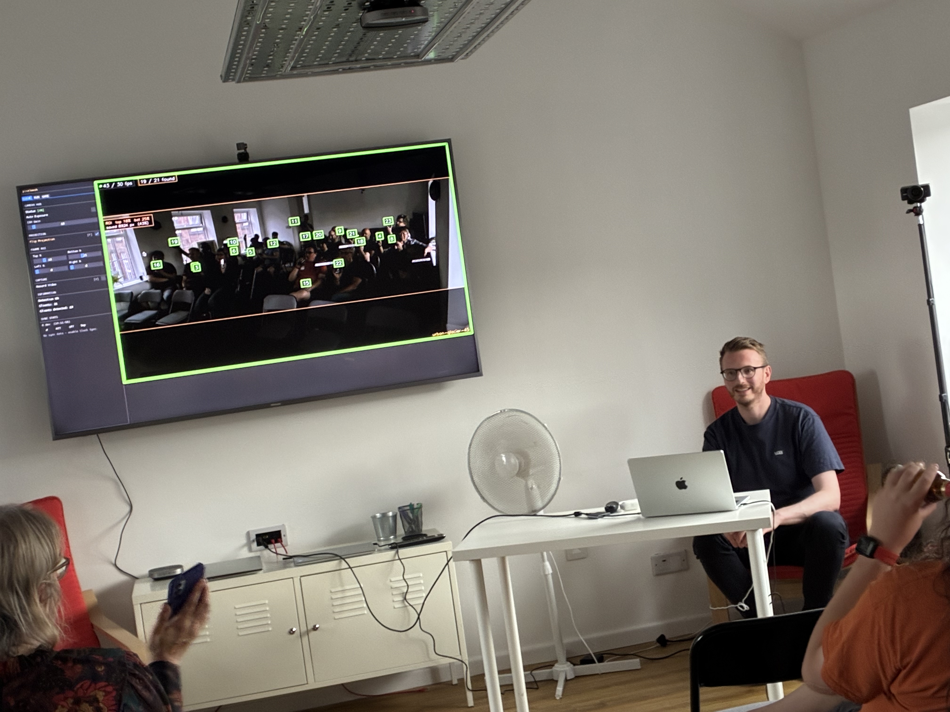 Screen shows camera locations, IDs. Adam sat controlling the system